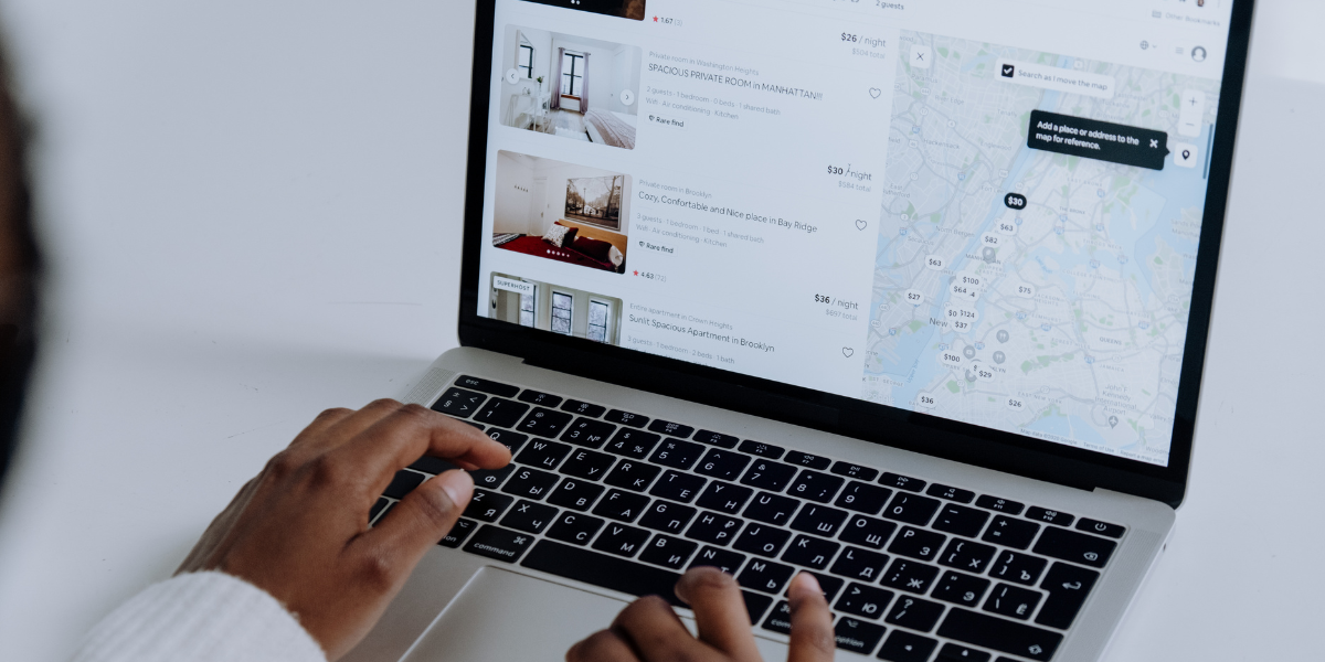 Hands on a laptop displaying the Airbnb interface, showcasing the best Airbnb management software.