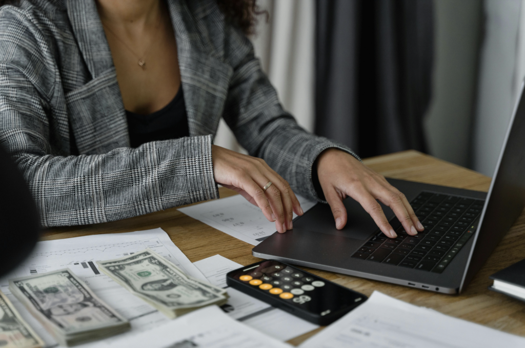 Table with financial documents, calculator, and laptop illustrating trust accounting practices in vacation rental management.