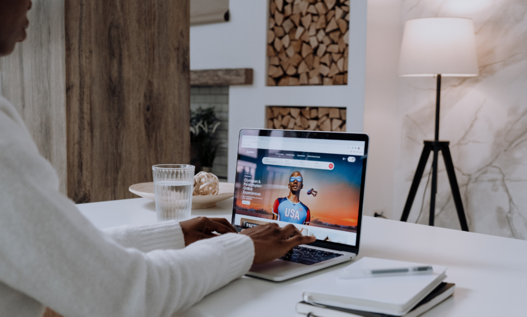 Person using a laptop to explore tips on how to manage and list houses online, with a modern workspace in the background.