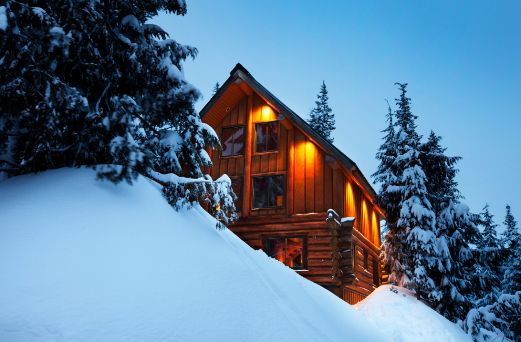 Cozy cabin illuminated at dusk in a snowy forest, representing tips on how to manage an Airbnb housing list effectively.