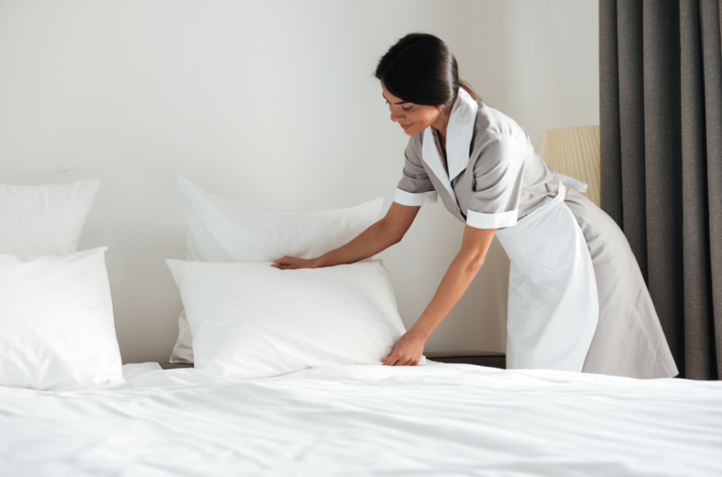 A professional housekeeper arranging pillows on a neatly made bed, highlighting the efficiency provided by the best housekeeping management software for vacation rentals.