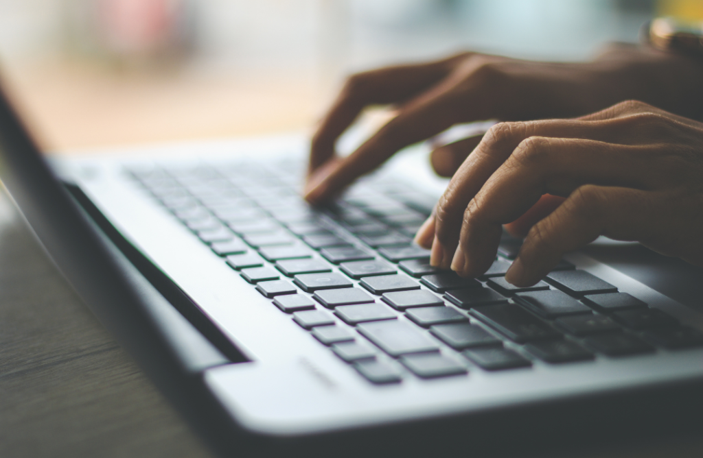 Hands typing on a laptop in a workspace, representing how the best vacation property management software simplifies operations.