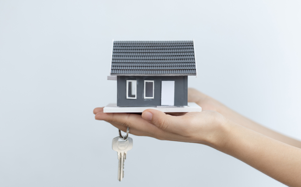 Hands holding a miniature house with a key, symbolizing ownership and tips on how to manage a vacation rental property effectively.