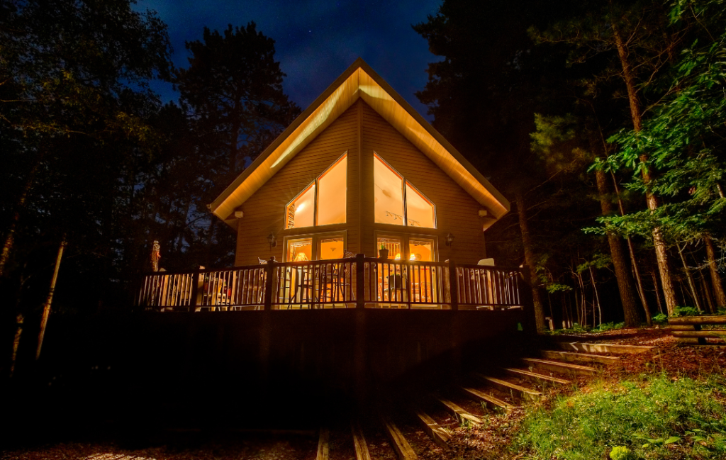 Beautiful cabin illuminated at night surrounded by trees, representing a potential rental property.